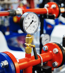 Drucksensoren im städtischen Heizsystem. Warmwasserrohre in einem industriellen Kesselraum. Mechanisches Barometer mit Pfeil zur Regelung der Geräteparameter (C) Dmitry Markov152